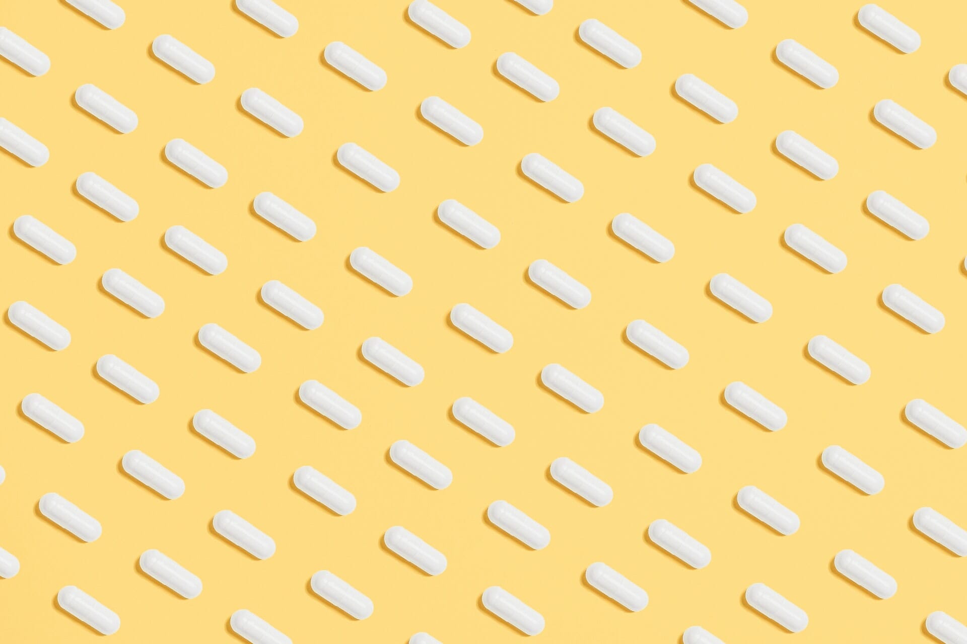 White tablet capsules on a yellow background