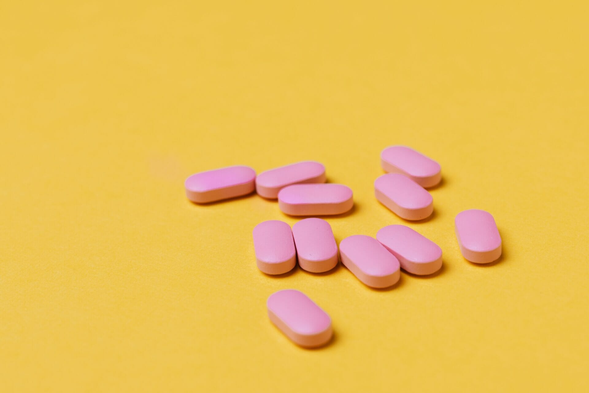 a number of pink tablets on a yellow surface