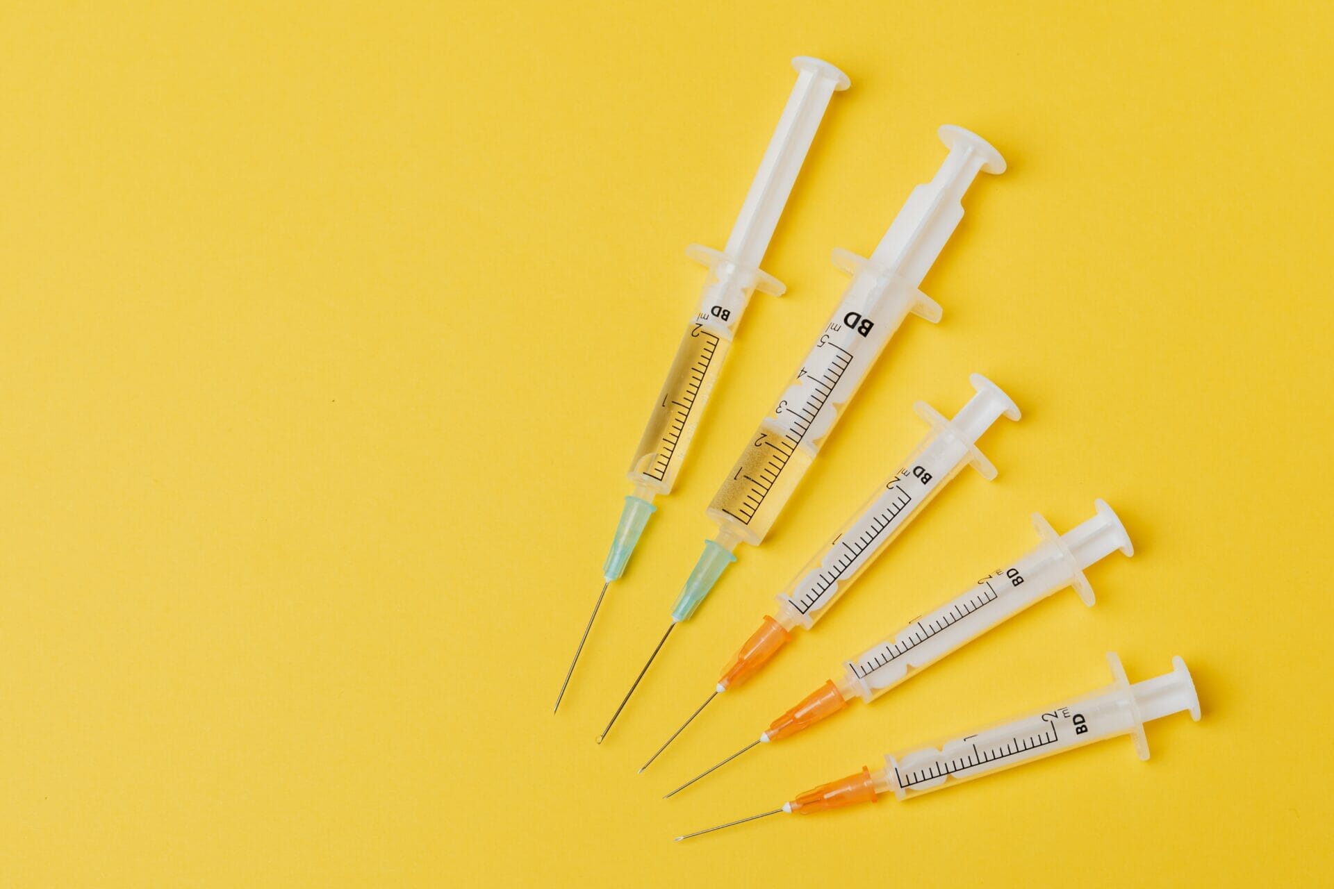Medical syringes on a plain yellow background